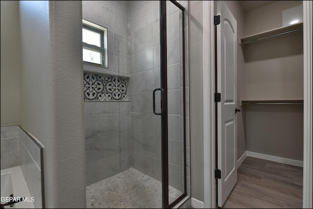 14844 Jack White Ave, El Paso, TX 79938 - bathroom featuring a shower stall, a walk in closet, wood finished floors, and baseboards