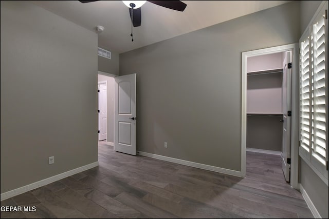 14844 Jack White Ave, El Paso, TX 79938 - unfurnished bedroom with a walk in closet, a closet, baseboards, a ceiling fan, and wood finished floors