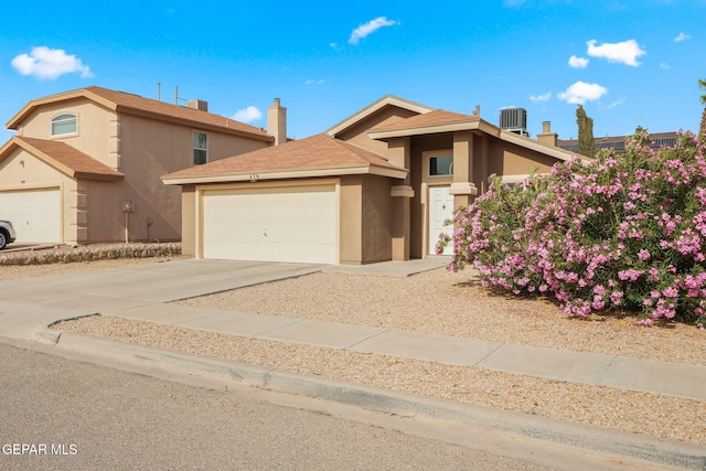 view of front facade with stucco siding, a garage, a chimney, and driveway