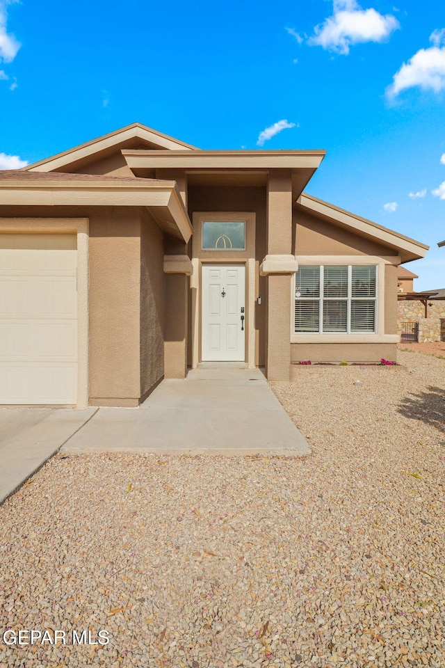 view of front of house featuring stucco siding, an attached garage, and driveway