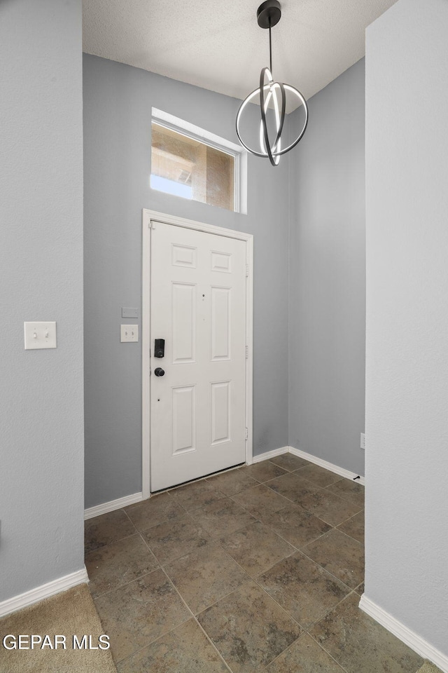 entryway with a chandelier and baseboards