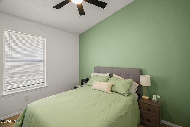 bedroom featuring vaulted ceiling, baseboards, ceiling fan, and a textured ceiling
