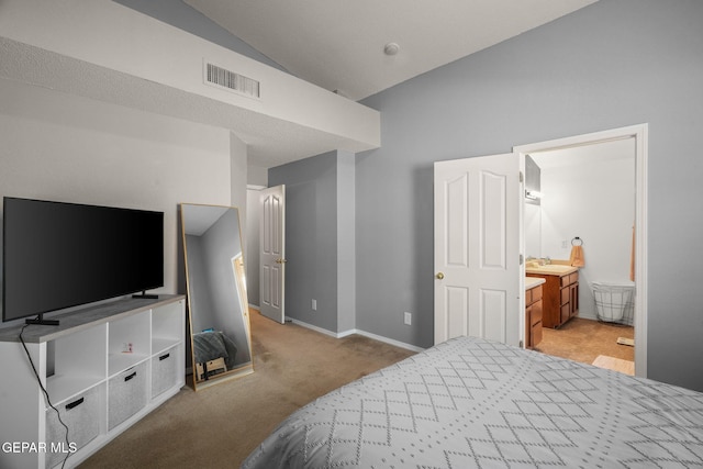 bedroom with carpet flooring, lofted ceiling, a sink, baseboards, and ensuite bath