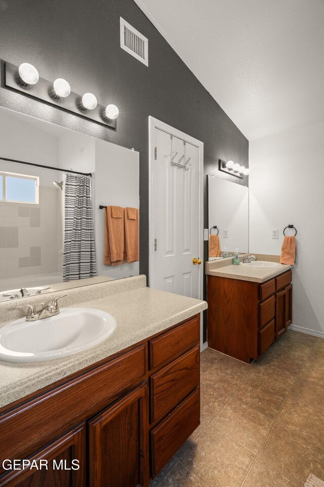 bathroom with two vanities, a shower with shower curtain, lofted ceiling, and tile patterned floors