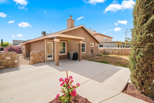 back of house featuring a chimney, stucco siding, a patio area, and central AC unit