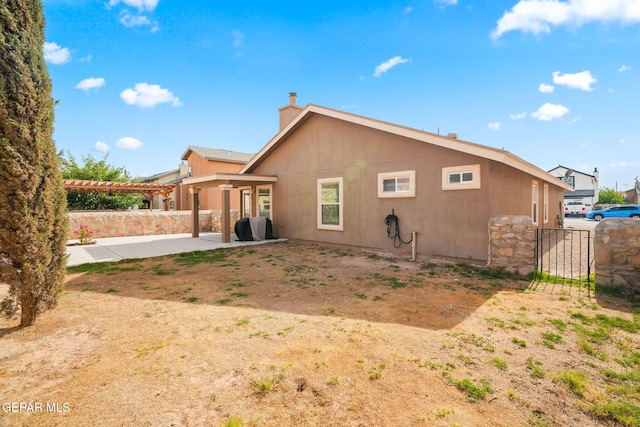 rear view of house with a pergola, fence, a patio, a chimney, and stucco siding