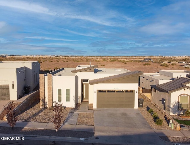 pueblo-style house with stucco siding, driveway, and a garage