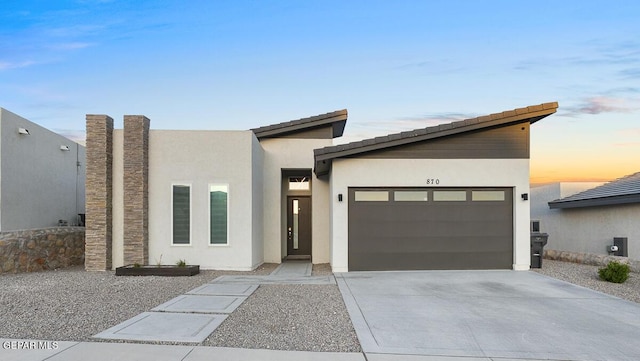 contemporary home with a garage, concrete driveway, and stucco siding