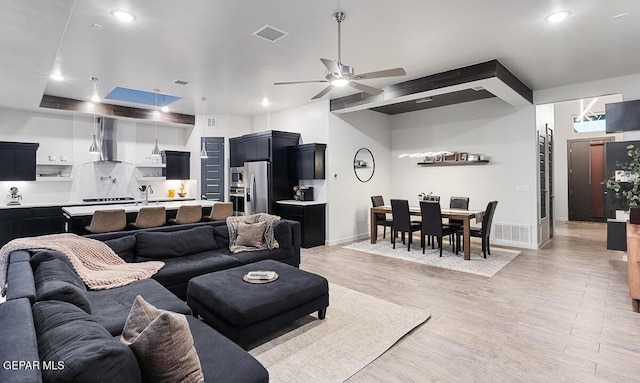 living room featuring light wood-type flooring, a ceiling fan, baseboards, and recessed lighting