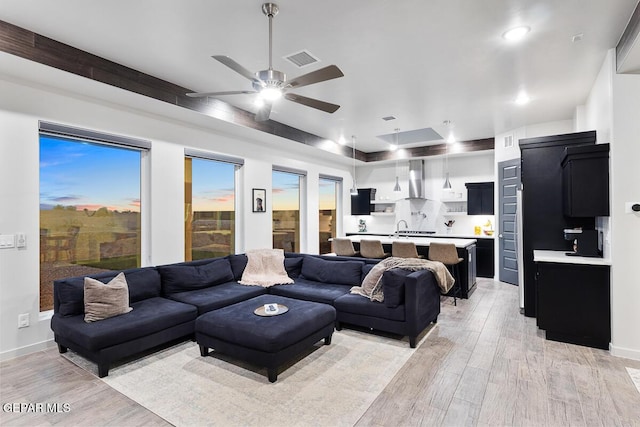 living area featuring light wood-style flooring, a ceiling fan, and baseboards