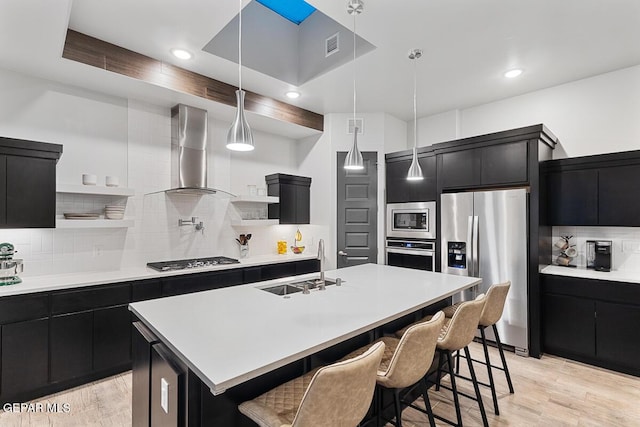 kitchen with dark cabinets, appliances with stainless steel finishes, open shelves, wall chimney exhaust hood, and recessed lighting