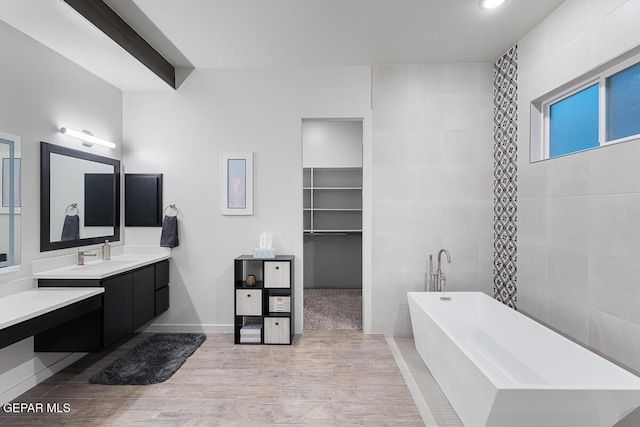 full bath featuring a soaking tub, vanity, wood finished floors, recessed lighting, and baseboards