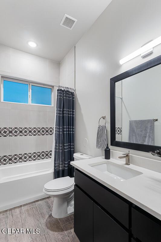 bathroom with toilet, shower / tub combo with curtain, wood tiled floors, vanity, and recessed lighting