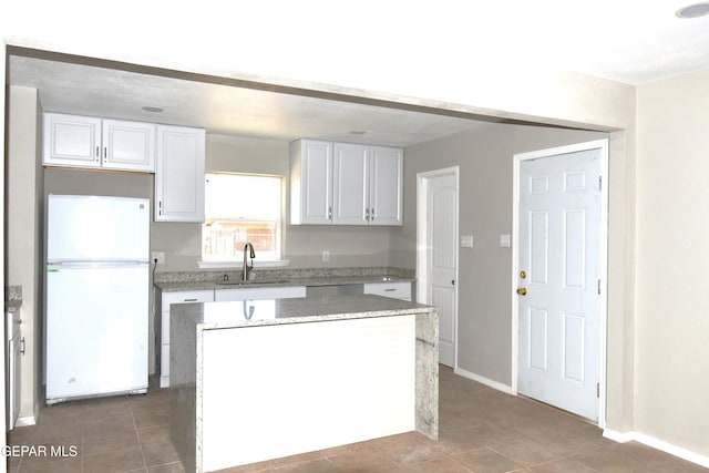 9207 Montgomery Dr, El Paso, TX 79924 - kitchen with freestanding refrigerator, a sink, white cabinets, a kitchen island, and tile patterned floors