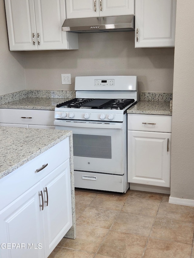 9207 Montgomery Dr, El Paso, TX 79924 - kitchen with white range with gas stovetop, under cabinet range hood, white cabinets, light stone countertops, and baseboards