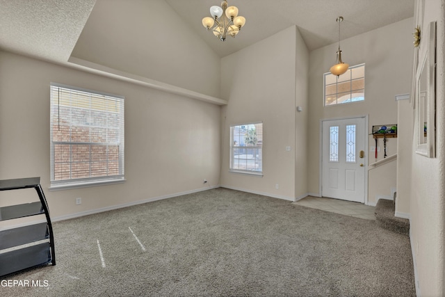 entryway featuring carpet floors, a high ceiling, a chandelier, and baseboards
