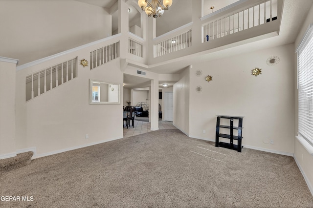 unfurnished living room with carpet flooring, a chandelier, baseboards, and a towering ceiling
