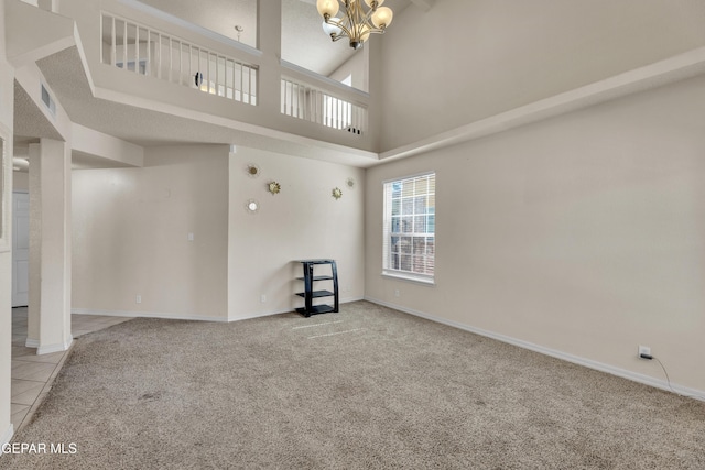 unfurnished living room with carpet, a chandelier, a towering ceiling, baseboards, and tile patterned flooring