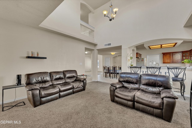carpeted living room featuring a chandelier and arched walkways