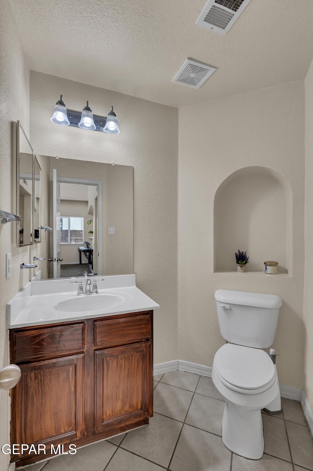 bathroom featuring a textured ceiling, toilet, vanity, tile patterned floors, and baseboards