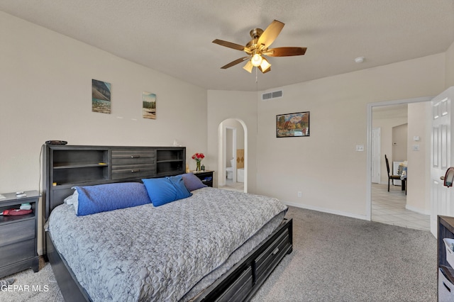 bedroom with arched walkways, light colored carpet, a ceiling fan, and baseboards