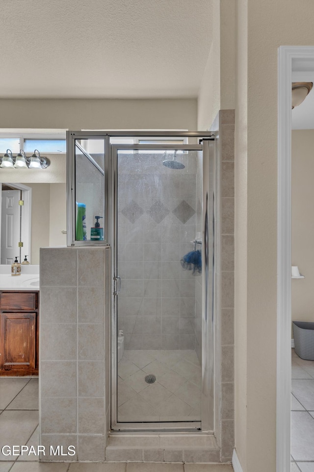 full bathroom featuring tile patterned flooring, a stall shower, and vanity