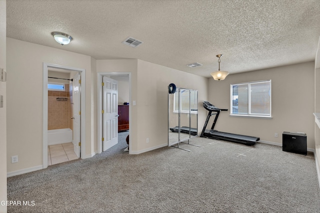 exercise room with carpet, a textured ceiling, and baseboards