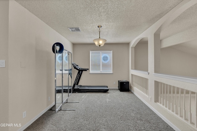 exercise area featuring carpet floors, a textured ceiling, and baseboards