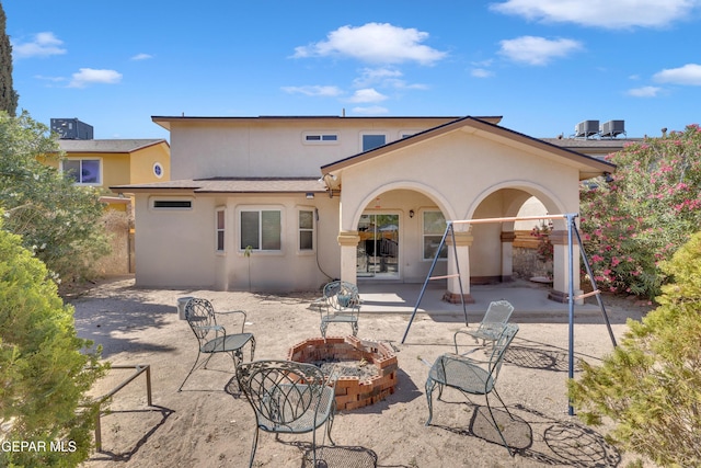 back of house with a fire pit, a patio area, stucco siding, and central air condition unit