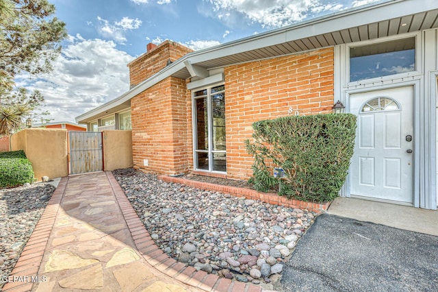 8024 Tonto Pl, El Paso, TX 79904 - doorway to property featuring a gate, brick siding, a chimney, and fence