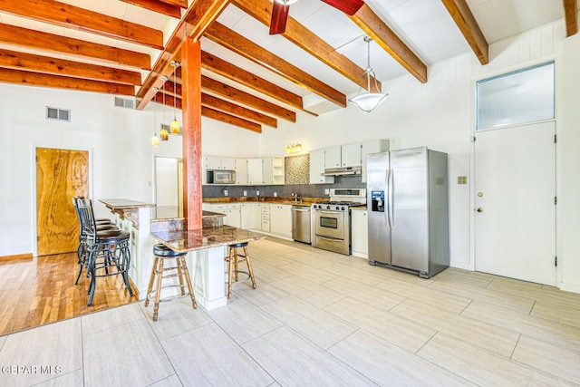 8024 Tonto Pl, El Paso, TX 79904 - kitchen with stainless steel appliances, under cabinet range hood, decorative backsplash, a kitchen bar, and beam ceiling