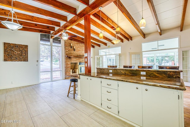 8024 Tonto Pl, El Paso, TX 79904 - kitchen featuring a fireplace, ceiling fan, a breakfast bar area, and pendant lighting