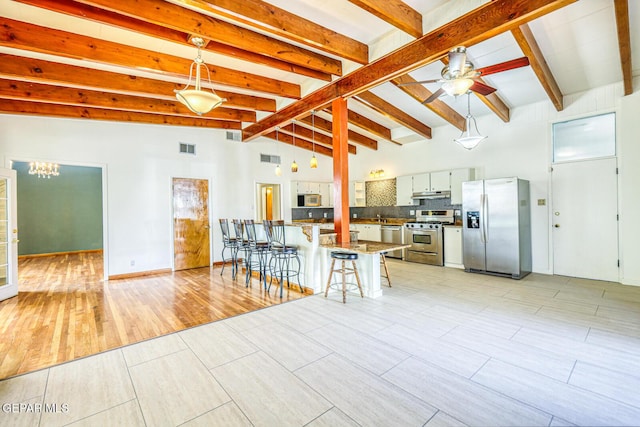 8024 Tonto Pl, El Paso, TX 79904 - kitchen featuring stainless steel appliances, a kitchen bar, under cabinet range hood, decorative backsplash, and a ceiling fan
