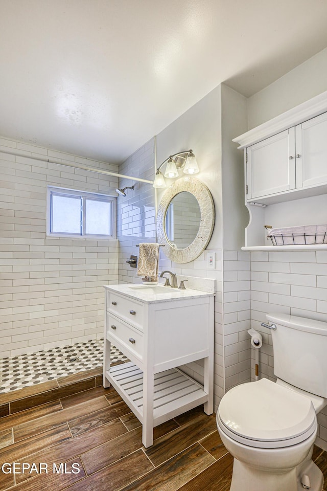 8024 Tonto Pl, El Paso, TX 79904 - bathroom featuring tile walls, toilet, a tile shower, wood finished floors, and vanity