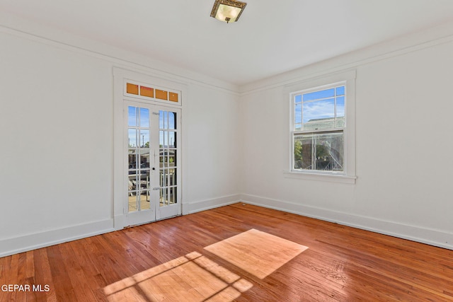 spare room with wood finished floors, healthy amount of natural light, and baseboards