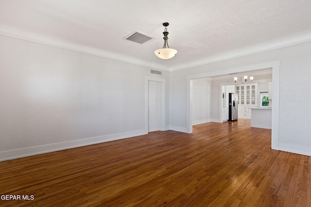 unfurnished room featuring a chandelier, wood-type flooring, and baseboards