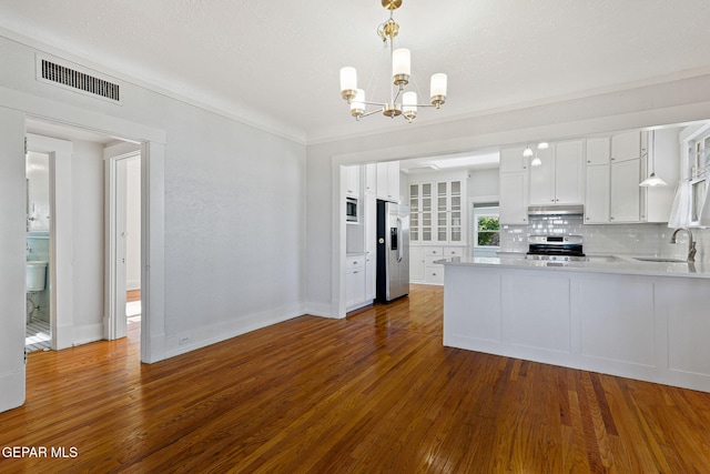 kitchen featuring appliances with stainless steel finishes, under cabinet range hood, a sink, light countertops, and dark wood-style flooring