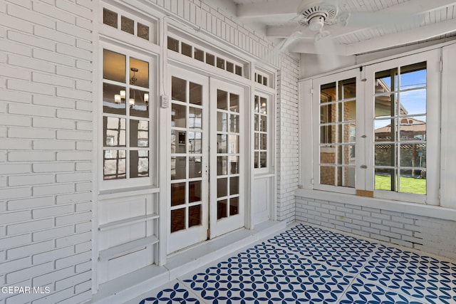 unfurnished sunroom with french doors, a ceiling fan, beam ceiling, and plenty of natural light