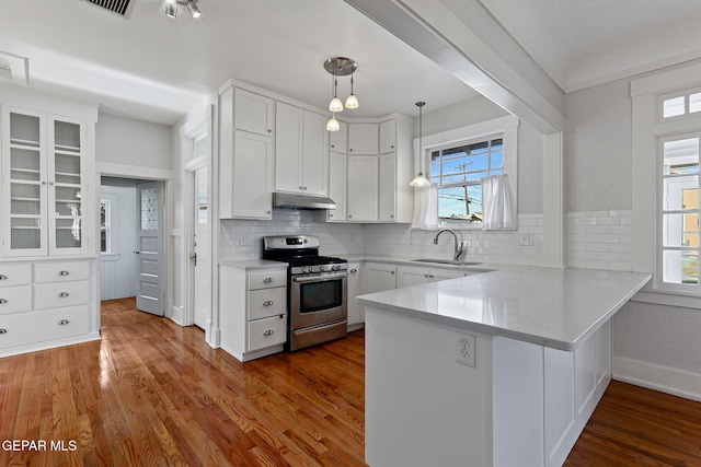 kitchen with stainless steel range with gas cooktop, under cabinet range hood, a peninsula, and plenty of natural light