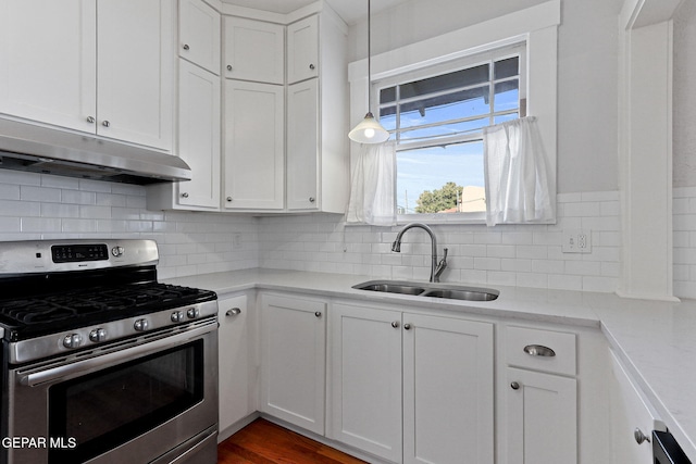kitchen featuring gas stove, a sink, under cabinet range hood, and white cabinets