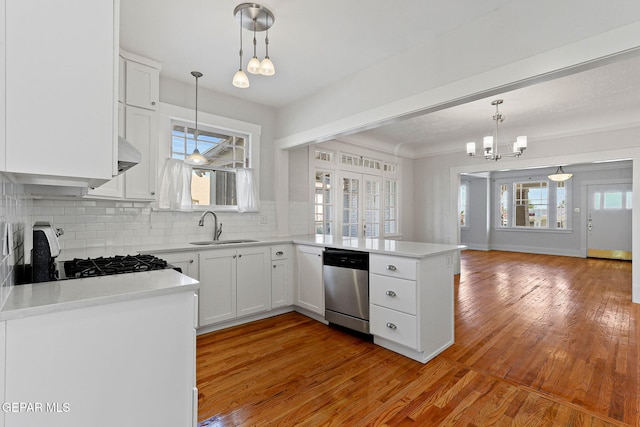 kitchen with a sink, dishwasher, a chandelier, a peninsula, and tasteful backsplash