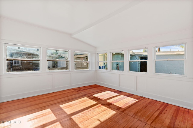 unfurnished sunroom with vaulted ceiling, hardwood / wood-style flooring, a wooden deck, and a decorative wall