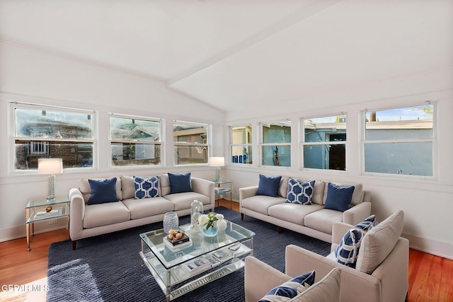 living room featuring wood finished floors, lofted ceiling, plenty of natural light, and baseboards
