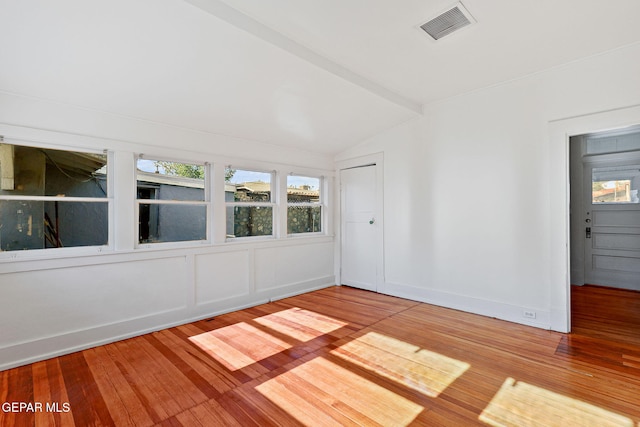 unfurnished room featuring lofted ceiling and hardwood / wood-style floors