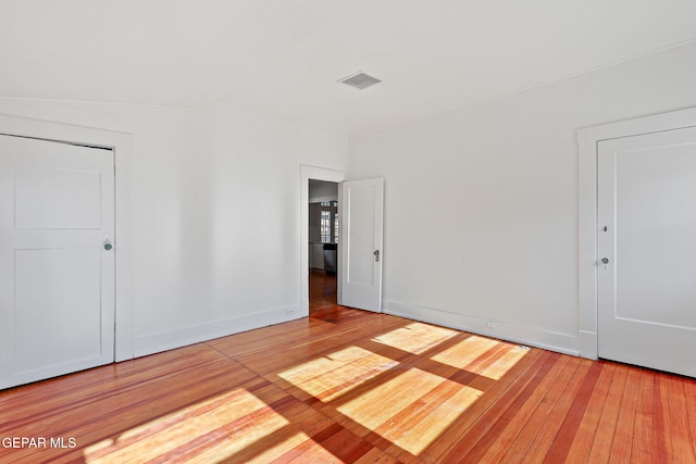 spare room with wood-type flooring and baseboards
