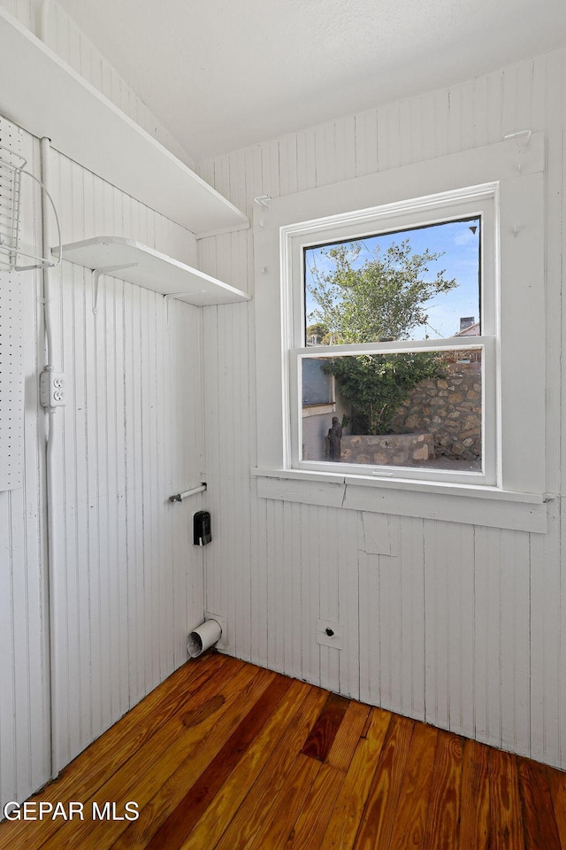 laundry area with wood finished floors and wooden walls