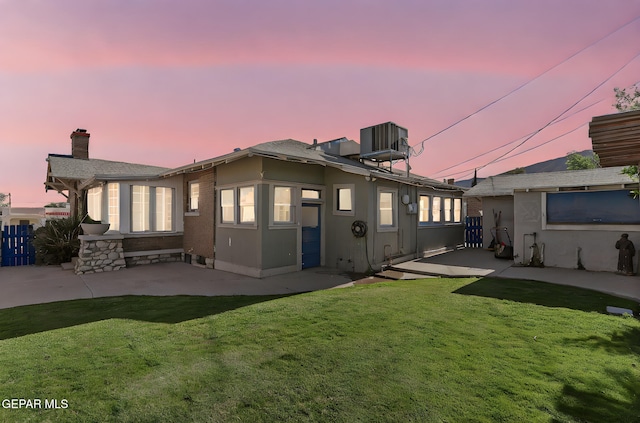 back of property at dusk with a patio area, cooling unit, and a chimney