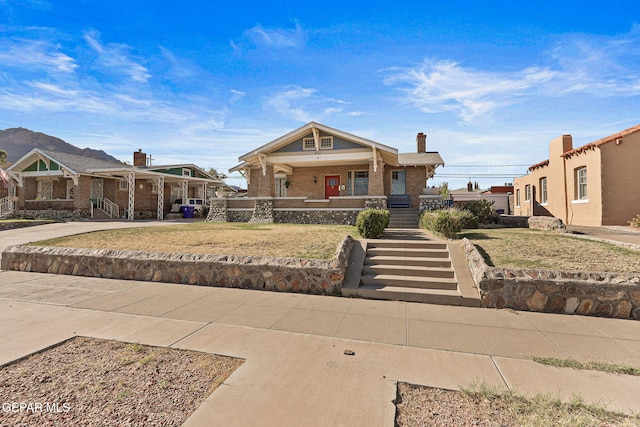 view of front of property featuring covered porch, brick siding, and a chimney