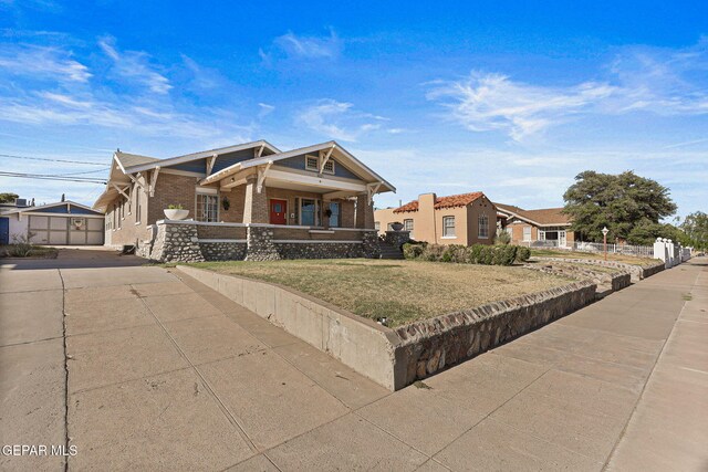 craftsman house with a porch, driveway, brick siding, and a front yard