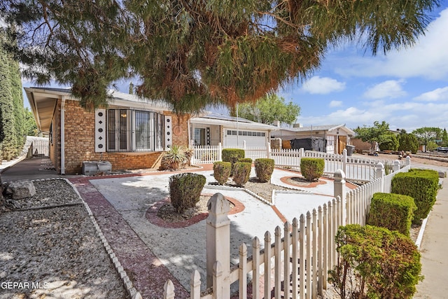 ranch-style home with brick siding, driveway, a fenced front yard, and a garage